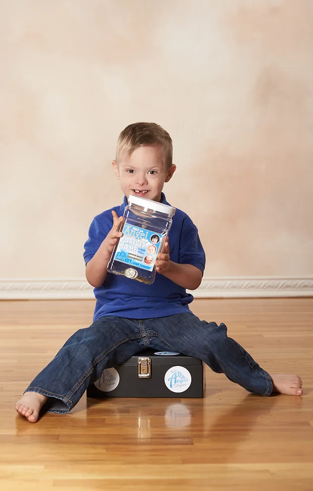 Little boy sitting down and holding Angel's donation jar